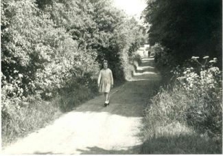 Eileen walking down Hill Road, taken in the late 1950s.  In the distance is the entrance to 'Jarvis Hall' | Harry Emery